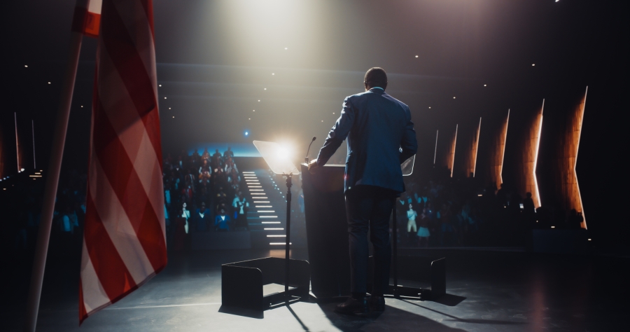 Politician standing at podium in darkened room
